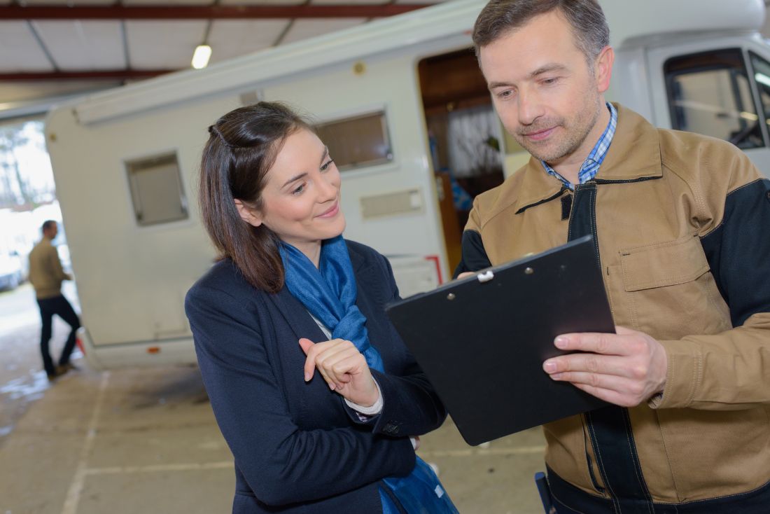 RV mechanic reviewing warranty paperwork with woman
