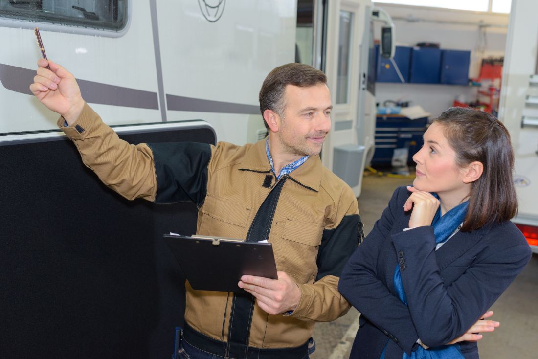 RV mechanic showing woman the damage to her window